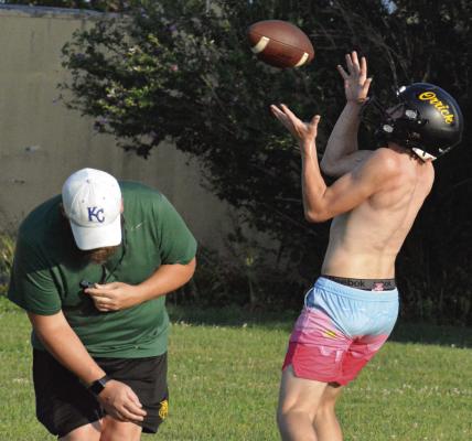 ORRICK ASSISTANT COACH Jake Waters (left) ducks as Gage Tebbe hauls in a deep ball during team camp for varsity 8-man football. SHAWN RONEY | Staff