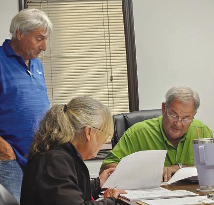RAY COUNTY 911 BOARD CHAIRMAN Paul Harris (right) signs the contract approving the purchase of a new dispatch radio system. MIRANDA JAMISON | Staff