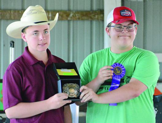 WESTON COVEY (left) helps display hardware won by Hunter Crowley in shooting sports during this year’s Ray County Fair in Richmond. SHAWN RONEY | Staff