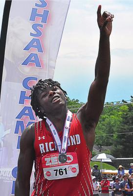 LOOKING TOWARD the crowd, Jacoby Johnson raises a finger in triumph as he stands on the awards podium after receiving his second-place medal in the 400-meter dash, and breaking his own school record, May 28 at Class 3 state track and field competition in Jefferson City. SHAWN RONEY | Staff