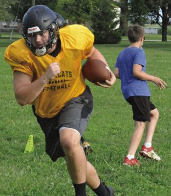 UPPERCLASSMAN TRENT WINDSOR (left) bulldozes downfield as he and fellow varsity Bearcats participate in pursuit drills with members of Orrick’s junior high 8-man football program during a team camp session. SHAWN RONEY | Staff