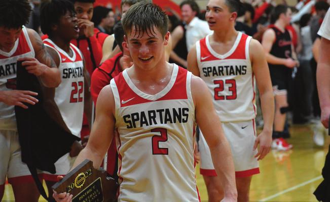 RICHMOND SENIOR guard Layne Cavanah looks satisfied as he walks off the court with the Class 4 District 15 championship plaque in hand after the Spartans’ March 4 win over Odessa at Oak Grove. SHAWN RONEY | Staff
