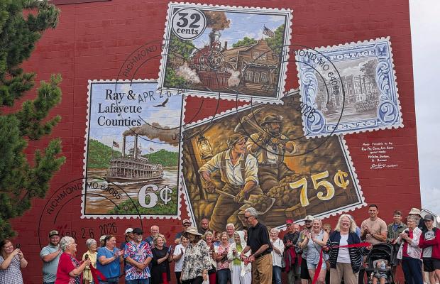 COMMUNITY MEMBERS celebrate the completion of a new mural at 206 West Main Street. The artwork brings together scenes from the community’s past while honoring the people and traditions that continue to define the city. MIRANDA JAMISON | Staff