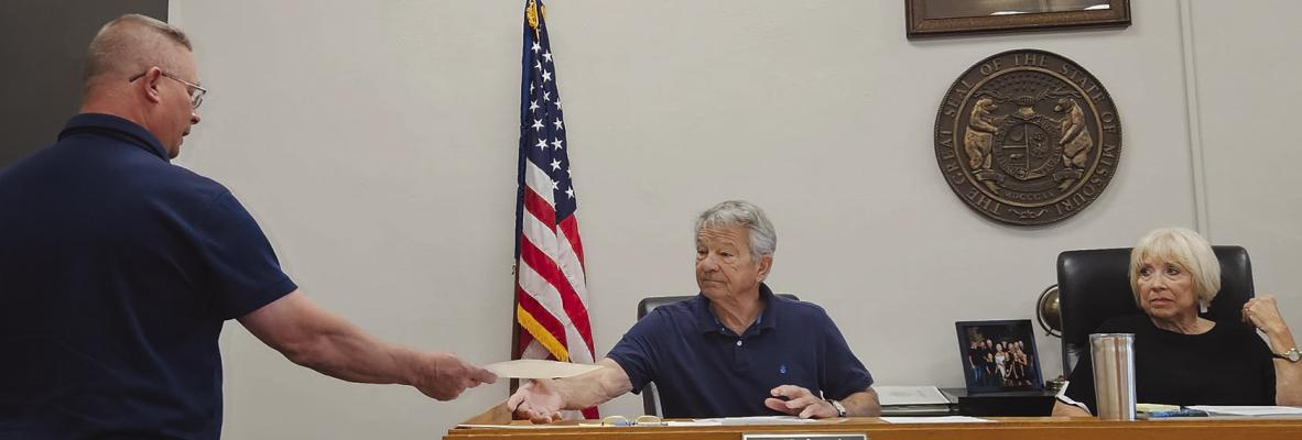 RAY COUNTY WATER DISTRICT NO. 2 Superintendent Jesse Howell (left) submits a written statement to commissioners requesting consideration of a one-time fee or bond system for future utility work performed within county road rights-of-way. MIRANDA JAMISON | Staff