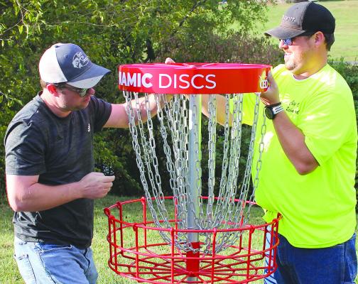 RICHMOND CITY Economic Developer James Gorham (left) places a disc golf basket with Richmond City Parks Superintendent Drew Brotherton. SOPHIA BALES | Staff