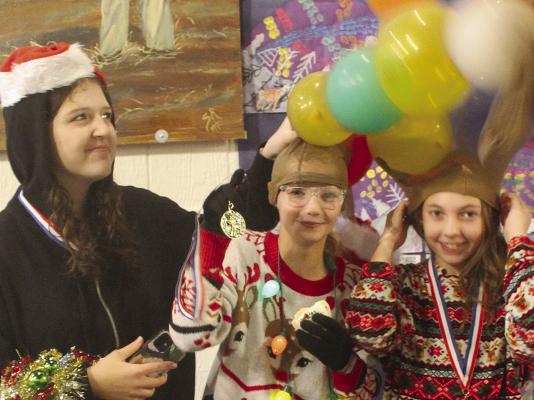 AUDREY THOMAS (from left), Myer McNary and Isabella Schoeneck try to keep their antlers standing up straight after participating in a contest at Orrick’s Old Fashion Christmas.
