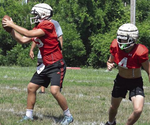 RICHMOND QUARTERBACK Jacob Lieberknecht (left) takes the snap from center, as Ryan Sharp bolts out of the backfield during a team camp session. SHAWN RONEY | Staff