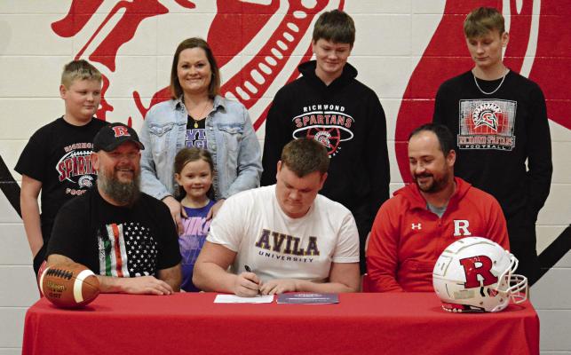 RICHMOND SENIOR Kail Farnan signs his letter of intent Feb. 29 in the Richmond High School gym to study and play football at Avila University in Kansas City. Also pictured are (from left), front row, Brian and Harper Farnan, and Richmond varsity football coach Nick Persell; back row, Liam, Tatha, Brody and Bryer Farnan. Story on page 8. SHAWN RONEY | Staff