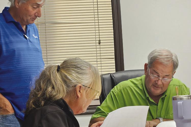RAY COUNTY 911 BOARD CHAIRMAN Paul Harris (right) signs the contract approving the purchase of a new dispatch radio system. MIRANDA JAMISON | Staff