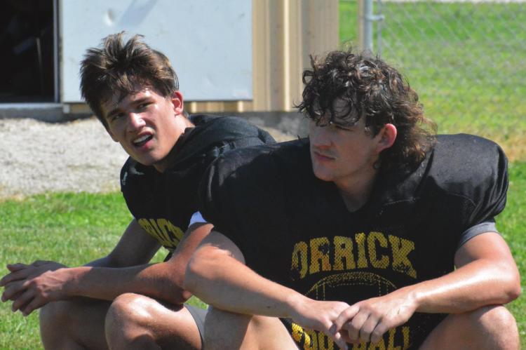 ZANDER STEVINSON, left, and Jaxon Miller take a breather during Orrick’s June 16 8-man football camp session on the Orrick practice field. SHAWN RONEY | Staff