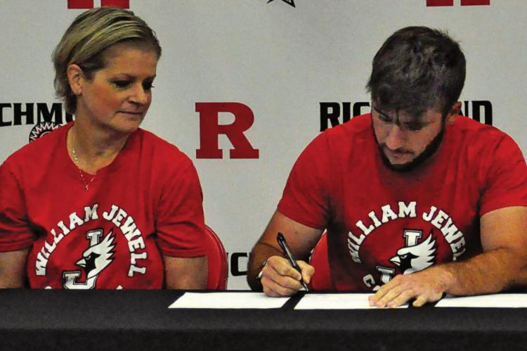 TIMMY HAMILTON signs his letter of intent to play men’s golf at William Jewell College as his mother, Jackie Sattler, watches. Also seated but not pictured are coach Murray Dennis and Hamilton’s stepfather Jeff Sattler. SHAWN RONEY | Staff