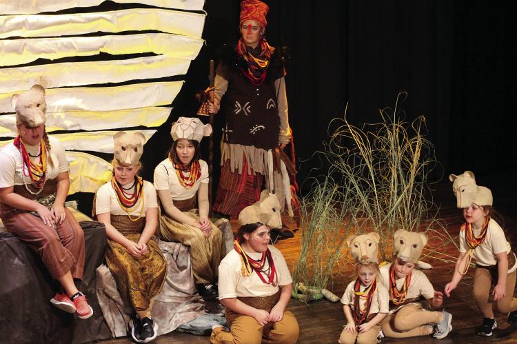 SOPHIA BALES | Staff LIONESSES ABIGAIL GARLAND (from left), Anna Garland, Kaeleigh Damron, Isbella Hendley, Gray McBee, Addison Garland and Margot Wiggins sing as Avis Rodenberg (standing) plays Rafiki in the musical.