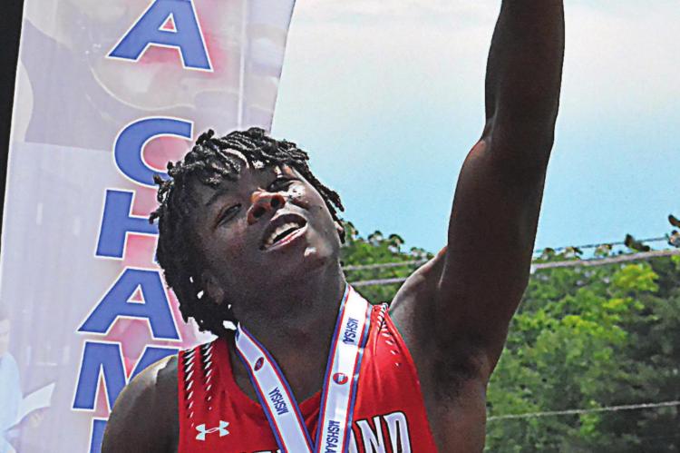 LOOKING TOWARD the crowd, Jacoby Johnson raises a finger in triumph as he stands on the awards podium after receiving his second-place medal in the 400-meter dash, and breaking his own school record, May 28 at Class 3 state track and field competition in Jefferson City. SHAWN RONEY | Staff
