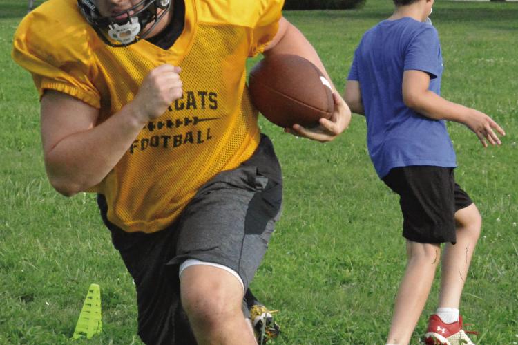 UPPERCLASSMAN TRENT WINDSOR (left) bulldozes downfield as he and fellow varsity Bearcats participate in pursuit drills with members of Orrick’s junior high 8-man football program during a team camp session. SHAWN RONEY | Staff