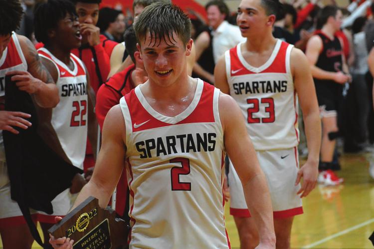 RICHMOND SENIOR guard Layne Cavanah looks satisfied as he walks off the court with the Class 4 District 15 championship plaque in hand after the Spartans’ March 4 win over Odessa at Oak Grove. SHAWN RONEY | Staff