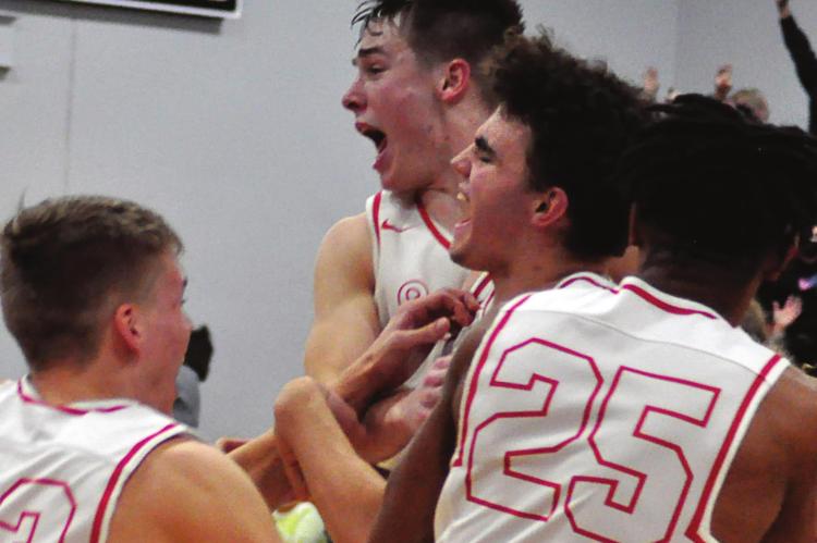 THE SPARTANS mob senior Wyatt Covey, center, after his game-winning steal and layup Monday night against visiting Knob Nobster. Junior Layne Cavanah leaps beside him. SHAWN RONEY | Staff