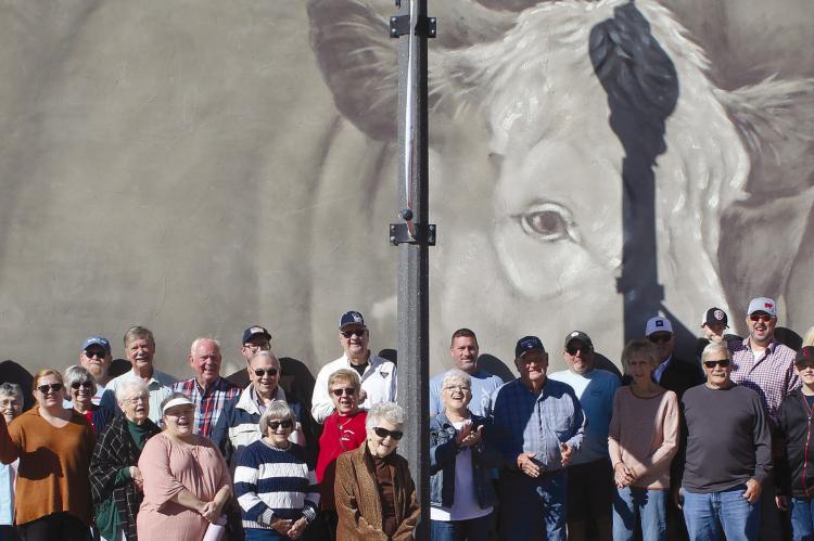 COMMUNITY MEMBERS celebrate Richmond’s newest mural with a recent ribbon-cutting on the historic Richmond Square. Organized by the Ray County Community Arts Association and painted by muralist Sam Welty, the piece honors local agricultural families while highlighting the area’s farming and cattle heritage. SHARON DONAT | Staff