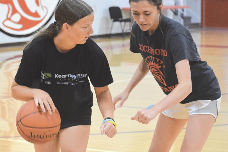 NEW RICHMOND varsity girls basketball coach Kaylee Vantrump, right, instructs Trinidy Fisk in protecting the ball while dribbling during an open gym session June 23 at Richmond High School. SHAWN RONEY | Staff