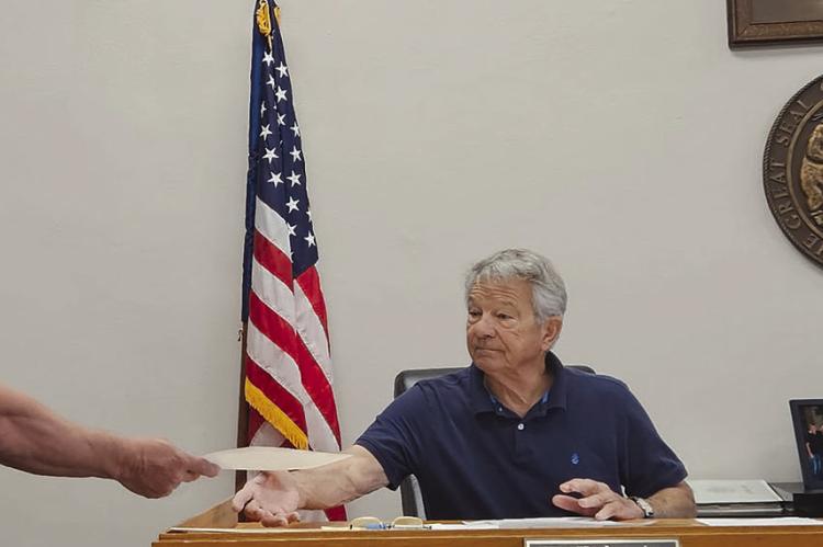 RAY COUNTY WATER DISTRICT NO. 2 Superintendent Jesse Howell (left) submits a written statement to commissioners requesting consideration of a one-time fee or bond system for future utility work performed within county road rights-of-way. MIRANDA JAMISON | Staff