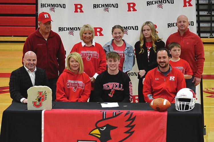 SENIOR LAYNE CAVANAH, front row-third from left, enjoys the moment of signing his letter of intent to play football for William Jewell College in Liberty with his family and Richmond varsity coach Nick Persell, seated next to him. SHAWN RONEY | Staff