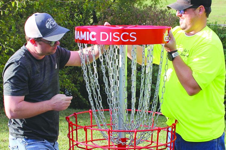 RICHMOND CITY Economic Developer James Gorham (left) places a disc golf basket with Richmond City Parks Superintendent Drew Brotherton. SOPHIA BALES | Staff