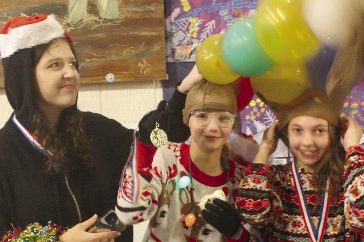 AUDREY THOMAS (from left), Myer McNary and Isabella Schoeneck try to keep their antlers standing up straight after participating in a contest at Orrick’s Old Fashion Christmas.