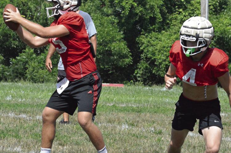 RICHMOND QUARTERBACK Jacob Lieberknecht (left) takes the snap from center, as Ryan Sharp bolts out of the backfield during a team camp session. SHAWN RONEY | Staff