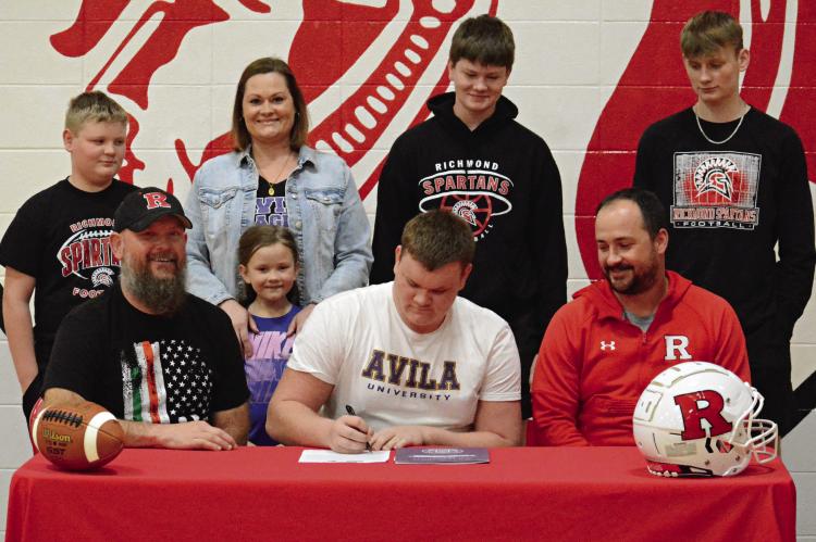 RICHMOND SENIOR Kail Farnan signs his letter of intent Feb. 29 in the Richmond High School gym to study and play football at Avila University in Kansas City. Also pictured are (from left), front row, Brian and Harper Farnan, and Richmond varsity football coach Nick Persell; back row, Liam, Tatha, Brody and Bryer Farnan. Story on page 8. SHAWN RONEY | Staff