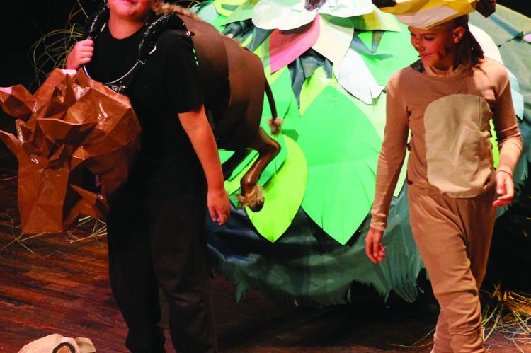MAVERICK PIERSON (left) and Gabe Rodenberg play Pumba and Timon. The duo looks upon Elijah Durham (on floor) who plays young Simba in scene nine.