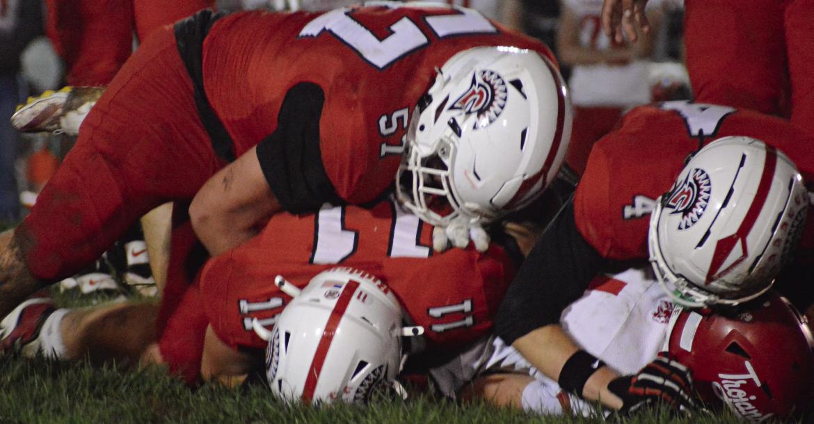 A TRIO OF SPARTANS (counterclockwise, from bottom), Colton Hewlett, Amos Farnan and Ryan Sharp, combine to make a tackle during Richmond’s homecoming win over Carrollton. SHAWN RONEY | Staff