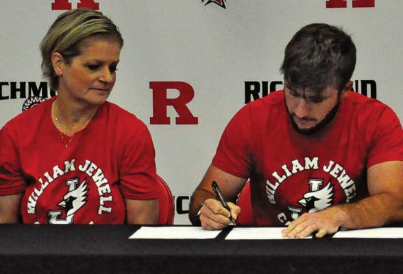 TIMMY HAMILTON signs his letter of intent to play men’s golf at William Jewell College as his mother, Jackie Sattler, watches. Also seated but not pictured are coach Murray Dennis and Hamilton’s stepfather Jeff Sattler. SHAWN RONEY | Staff
