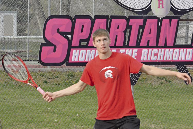 RICHMOND SENIOR Gabe Baker keeps his eyes on the tennis ball as he waits to hit a forehand shot during his singles match with Knob Noster’s Noah Schoepke Monday at Maurice Roberts Park. SHAWN RONEY | Staff