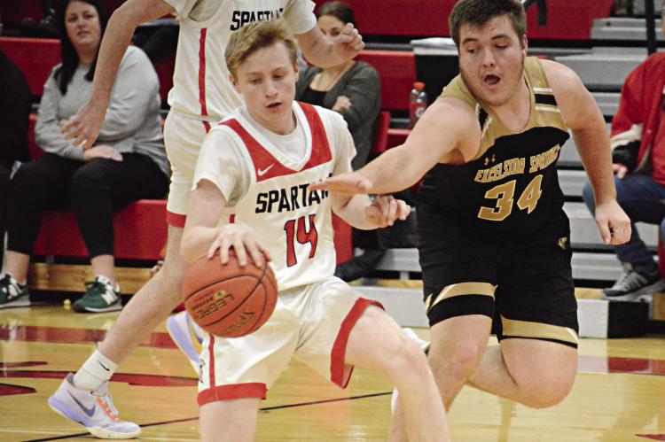NOLAN QUICK, a first-year high schooler, shields the ball from Excelsior Springs senior Ryan Gluhm during the fourth quarter of the Spartans’ 71-43 victory Tuesday night at Richmond High School. SHAWN RONEY | Staff
