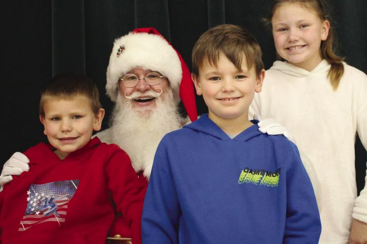 SIBLINGS MICHAEL (from left), John Jr. and Melody Powell sit with Santa at Richmond Middle School last week. SOPHIA BALES | Staff