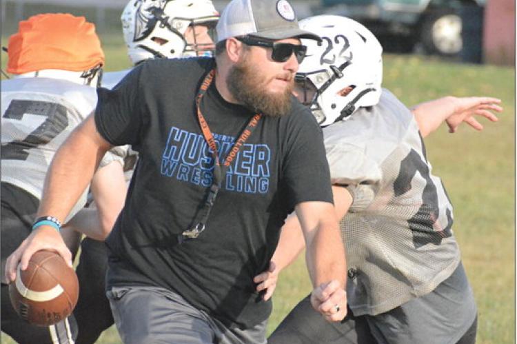 WEARING HIS ballcap, shades and coaching whistle, Norborne Hardin-Central varsity 8-man football coach Andrew Watson rolls out Tuesday on the Hardin-Central practice field to help similuate Braymer/Breckenridge’s offense. SHAWN RONEY | Staff