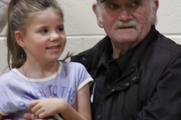 MILA NICOLL (left) sits with her grandfather, Clyde Hines, after the Dear Elementary Veterans Assembly last week. SOPHIA BALES | Staff