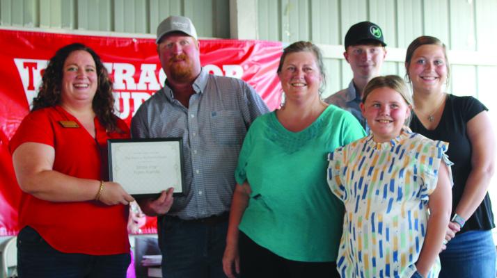 EXTENSION ENGAGEMENT SPECIALIST Chelsea Corkins (left) presents the 2024 Ray County Farm Award to Jeremy McGinnis and family, including wifem Jamie, and children Kaden, Amaryllis and Kassie. SHARON DONAT | Staff