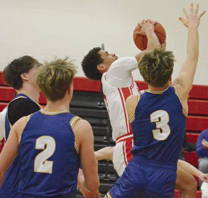 BRICE DOME (center) clutches onto the basketball as he drives into a nest of Hornets to attempt a contested layup during Richmond’s fifth-place game with Penney of Hamilton in the Lawson Invitational Tournament. SHAWN RONEY | Staff