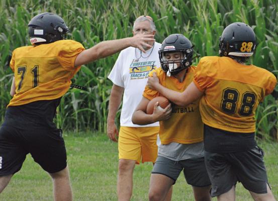 TUCKER GREER (No. 71) and Ashton Toland (No. 88) display their pass rushing skills during Orrick’s 8-man football team camp Monday on the program’s practice field. SHAWN RONEY | Staff