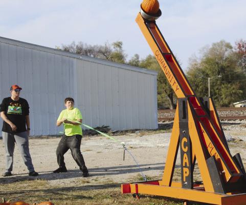 COMMUNITY AT PLAY Implementer Caitlin Crowley supervises Logan Braeckel as he pulls the cord to launch his pumpkin. SHARON DONAT | Staff