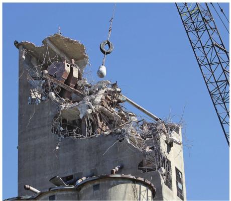 UNDER A BLUE SKY, a wrecking ball swings back and forth, pounding the concrete body and sometimes dropping destructively into the organs of the old grain elevator in Richmond as part of the slow, careful process of demolition. Last week’s work is sure to extend into this week and beyond. J.C. VENTIMIGLIA | Staff