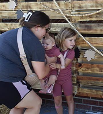 DARCY HUMDLEY (LEFT) places daughter Elie into Maylee’s arms for a photo-op.