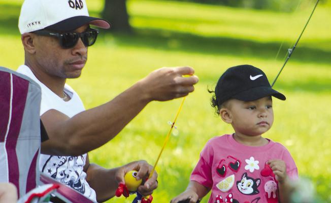 TEVIN ROBINSON helps his daughter, Maven, prepare her fishing line during the fishing competition. SHARON DONAT | Staff