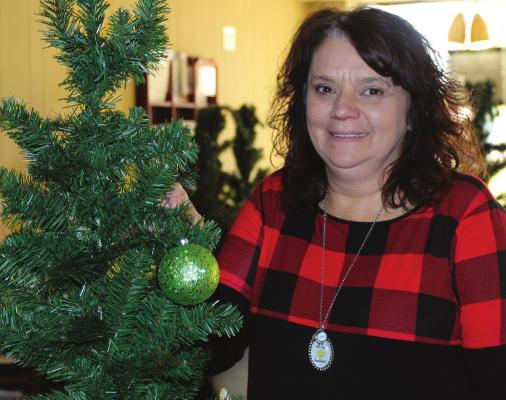 THE ANNUAL Christmas Tree Extravaganza will location has changed. Rather than being at the Richmond Area Chamber of Commerce Office, the event will open Friday at Shirkey Golf Course. Chamber Director Carolyn Arney places an ornament on the first of 35 trees that will be decorated. J.C. VENTIMIGLIA | Staff