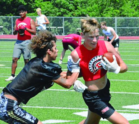 BRYER FARNAN shields the ball with his left arm as he’s “tackled” with a two-hand touch after a short catch-and-run play for the Spartans during Tuesday’s 7-on-7 scrimmage with Excelsior Springs at Tiger Stadium. SHAWN RONEY | Staff