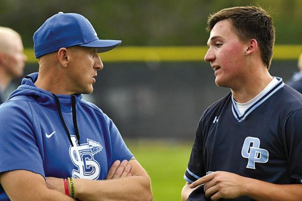 CALE LYONS (left) confers with a player during a previous baseball practice. Lyons balances coaching and teaching with ongoing service in the Missouri Army National Guard. Submitted