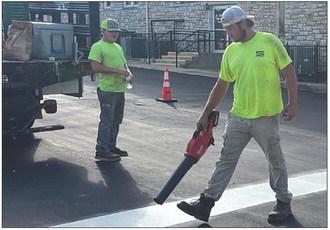 K AND G STRIPING LLC staffers Tyler Geesaman (left) and Bobby Crossley work on N.W. Main Street Wednesday morning. SOPHIA BALES | Staff
