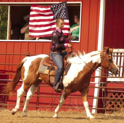 Alexis Reeves carries the American Flag with her horse, Hank, while guests stood for the National Anthem.