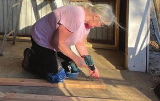 WORKING on the floor in the expanding facility, volunteer Gina Harmon, Richmond, helps out at Autumn Acres Animal Rescue.
