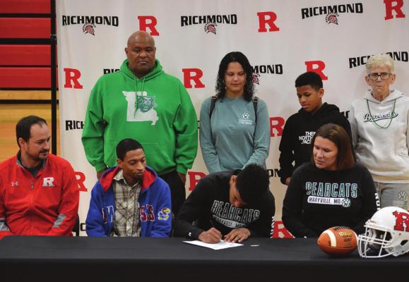 SURROUNDED by his coach and others close to him, Richmond senior Jordan Alexander signs his letter of intent to play football at NWMSU. SHAWN RONEY | Staff